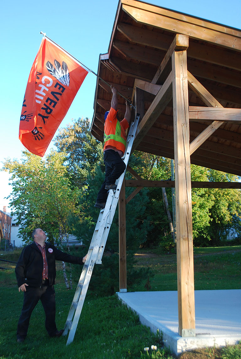 Campbell’s Bay mayor, Maurice Beauregard assists municipal worker Denis Dagenais as he raises the flag to commemorate the first Day of Truth and Reconcilliation.